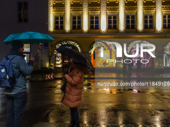 On a rainy evening in Munich, Bavaria, Germany, on December 8, 2024, during the Christmas season, the streets come alive with the glow of fe...