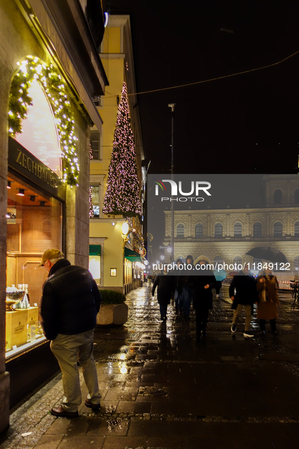 On a rainy evening in Munich, Bavaria, Germany, on December 8, 2024, during the Christmas season, the streets come alive with the glow of fe...