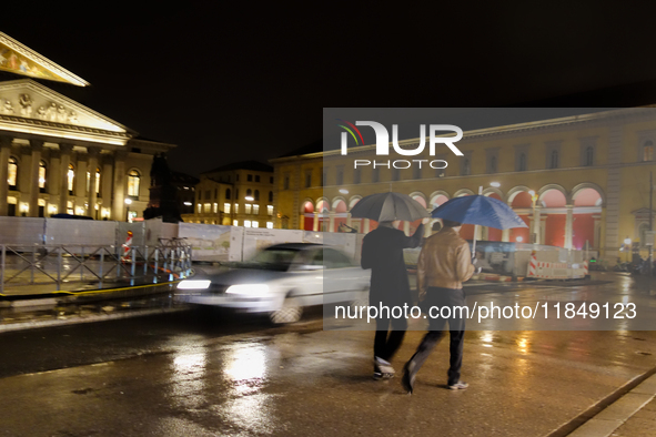 Two men walk on the streets of Munich, Bavaria, Germany, on December 8, 2024, with an umbrella during the Christmas season. 