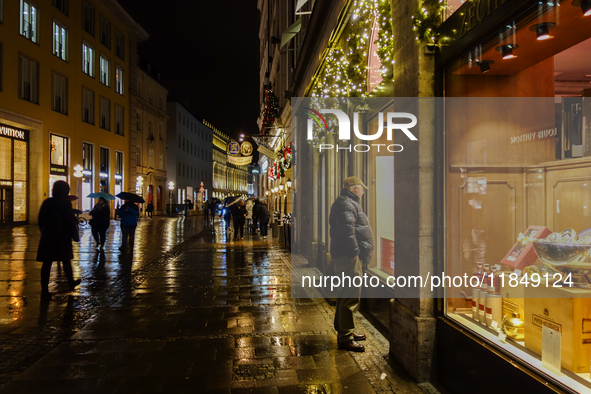 On a rainy evening in Munich, Bavaria, Germany, on December 8, 2024, during the Christmas season, the streets come alive with the glow of fe...