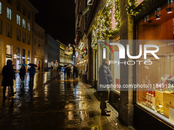 On a rainy evening in Munich, Bavaria, Germany, on December 8, 2024, during the Christmas season, the streets come alive with the glow of fe...