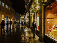 On a rainy evening in Munich, Bavaria, Germany, on December 8, 2024, during the Christmas season, the streets come alive with the glow of fe...