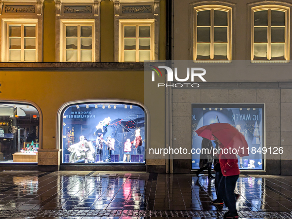 On a rainy evening in Munich, Bavaria, Germany, on December 8, 2024, during the Christmas season, the streets come alive with the glow of fe...