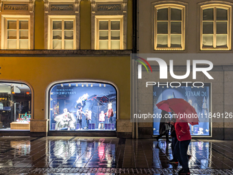 On a rainy evening in Munich, Bavaria, Germany, on December 8, 2024, during the Christmas season, the streets come alive with the glow of fe...