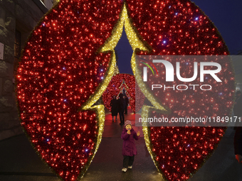 A girl looks at a glowing installation during the Christmas season in Kharkiv, Ukraine, on December 7, 2024. (