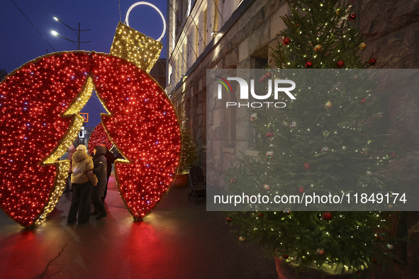 People stand under a glowing installation during the Christmas season in Kharkiv, Ukraine, on December 7, 2024. 