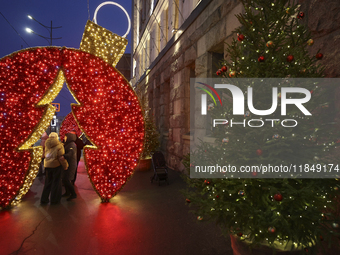 People stand under a glowing installation during the Christmas season in Kharkiv, Ukraine, on December 7, 2024. (