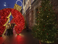 People stand under a glowing installation during the Christmas season in Kharkiv, Ukraine, on December 7, 2024. (