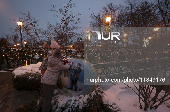 Two girls explore a big bauble during the Christmas season in Kharkiv, Ukraine, on December 7, 2024. 