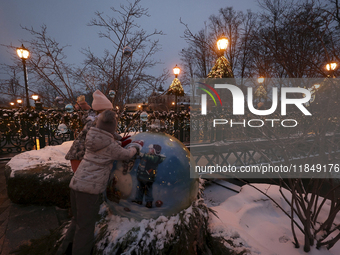 Two girls explore a big bauble during the Christmas season in Kharkiv, Ukraine, on December 7, 2024. (