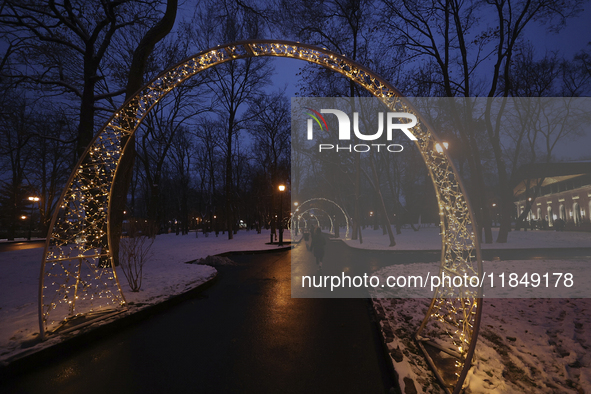 Arches decorated with string lights illuminate an alley in the park during the Christmas season in Kharkiv, Ukraine, on December 7, 2024. 