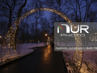 Arches decorated with string lights illuminate an alley in the park during the Christmas season in Kharkiv, Ukraine, on December 7, 2024. (