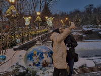 Women take a selfie in front of Christmas decorations in Kharkiv, Ukraine, on December 7, 2024. (