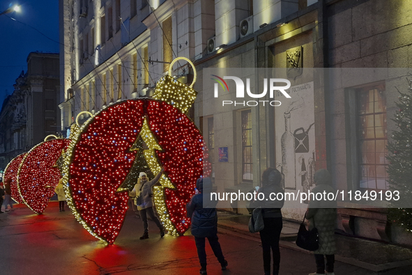 A woman poses for a photo at a bauble-shaped installation during the Christmas season in Kharkiv, Ukraine, on December 7, 2024. NO USE RUSSI...