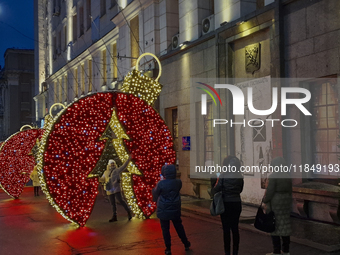 A woman poses for a photo at a bauble-shaped installation during the Christmas season in Kharkiv, Ukraine, on December 7, 2024. NO USE RUSSI...