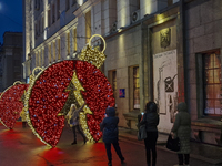 A woman poses for a photo at a bauble-shaped installation during the Christmas season in Kharkiv, Ukraine, on December 7, 2024. NO USE RUSSI...