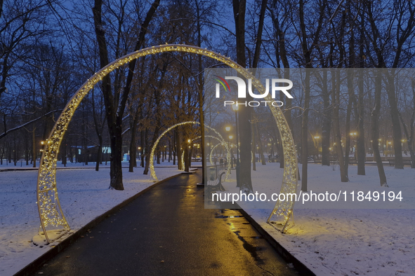 Arches decorated with string lights illuminate an alley in the park during the Christmas season in Kharkiv, Ukraine, on December 7, 2024. 