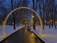 Arches decorated with string lights illuminate an alley in the park during the Christmas season in Kharkiv, Ukraine, on December 7, 2024. (