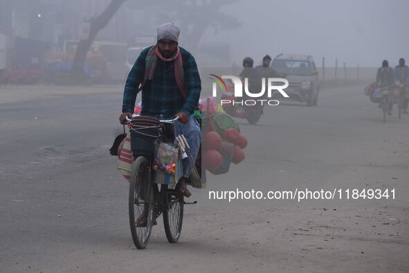 Vendors move through dense fog on a winter morning in Nagaon District, Assam, India, on December 8, 2024. 