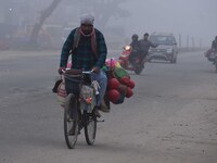 Vendors move through dense fog on a winter morning in Nagaon District, Assam, India, on December 8, 2024. (