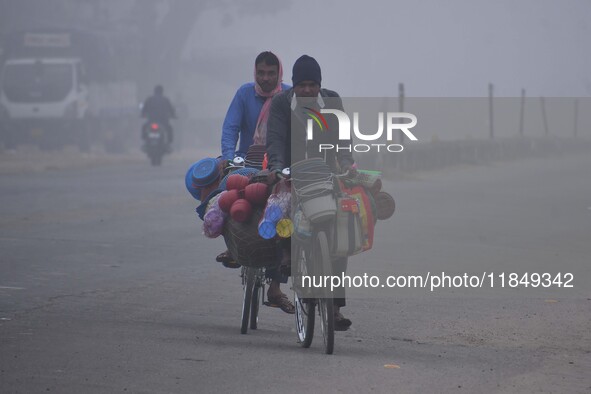 Vendors move through dense fog on a winter morning in Nagaon District, Assam, India, on December 8, 2024. 