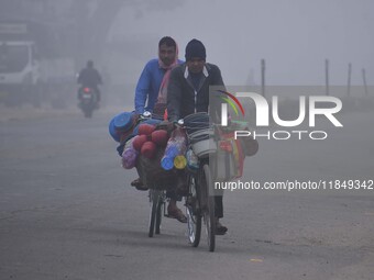 Vendors move through dense fog on a winter morning in Nagaon District, Assam, India, on December 8, 2024. (