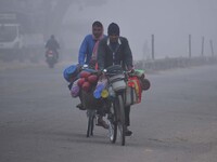 Vendors move through dense fog on a winter morning in Nagaon District, Assam, India, on December 8, 2024. (