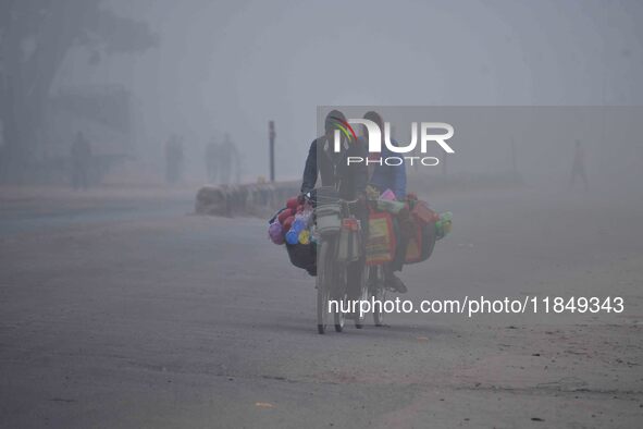 Vendors move through dense fog on a winter morning in Nagaon District, Assam, India, on December 8, 2024. 