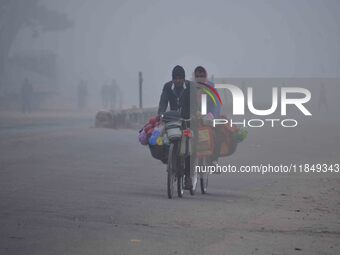 Vendors move through dense fog on a winter morning in Nagaon District, Assam, India, on December 8, 2024. (