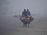 Vendors move through dense fog on a winter morning in Nagaon District, Assam, India, on December 8, 2024. (