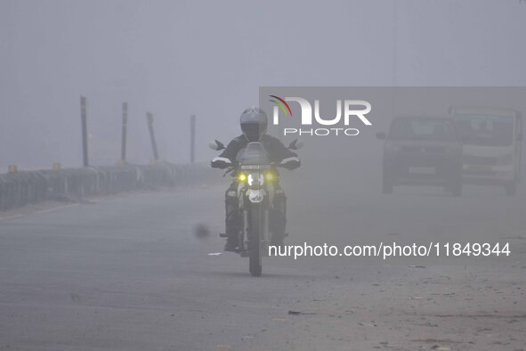 A bike rider moves through dense fog on a winter morning in Nagaon District, Assam, India, on December 8, 2024. 