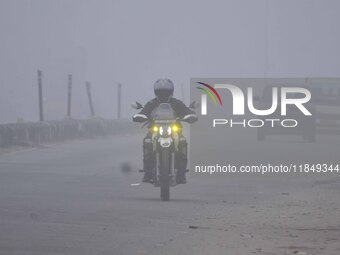 A bike rider moves through dense fog on a winter morning in Nagaon District, Assam, India, on December 8, 2024. (