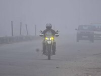 A bike rider moves through dense fog on a winter morning in Nagaon District, Assam, India, on December 8, 2024. (