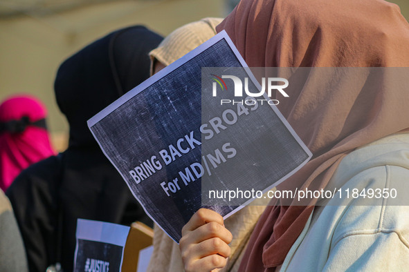 A student of Bachelor of Medicine and Bachelor of Surgery (MBBS) holds a placard during a protest against excessive reservation in competiti...