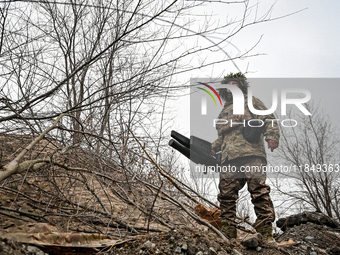 A serviceman of a self-propelled howitzer crew from Ukraine's 118th Separate Mechanized Brigade uses an anti-drone rifle while on a mission...