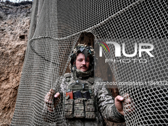 An artilleryman of Ukraine's 118th Separate Mechanized Brigade stands by a net that masks the space where a self-propelled howitzer is kept...