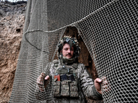 An artilleryman of Ukraine's 118th Separate Mechanized Brigade stands by a net that masks the space where a self-propelled howitzer is kept...