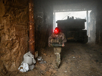 An artilleryman of Ukraine's 118th Separate Mechanized Brigade carries a 155mm shell for a self-propelled howitzer while on a mission in the...