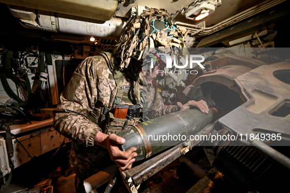 An artilleryman of Ukraine's 118th Separate Mechanized Brigade loads a shell inside a self-propelled howitzer while on a mission in the Zapo...