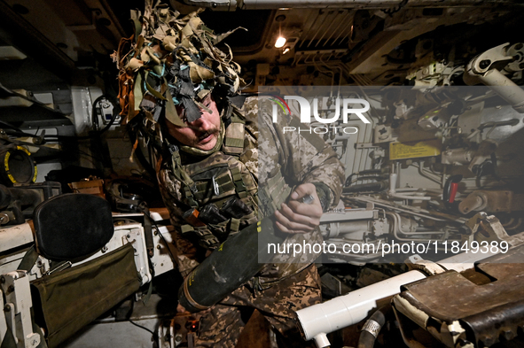 An artilleryman of Ukraine's 118th Separate Mechanized Brigade loads a shell inside a self-propelled howitzer while on a mission in the Zapo...