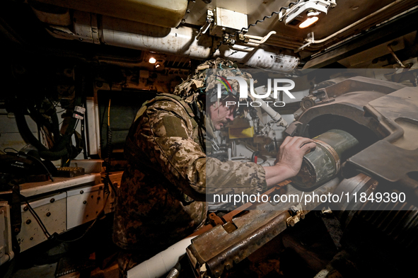 An artilleryman of Ukraine's 118th Separate Mechanized Brigade loads a shell inside a self-propelled howitzer while on a mission in the Zapo...