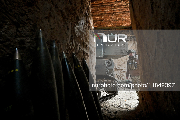 An artilleryman of a self-propelled howitzer crew from Ukraine's 118th Separate Mechanized Brigade is seen from an ammunition storage space...