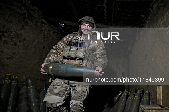 An artilleryman of Ukraine's 118th Separate Mechanized Brigade carries a 155mm shell for a self-propelled howitzer while on a mission in the...