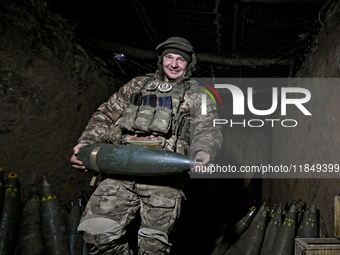 An artilleryman of Ukraine's 118th Separate Mechanized Brigade carries a 155mm shell for a self-propelled howitzer while on a mission in the...