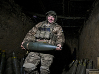 An artilleryman of Ukraine's 118th Separate Mechanized Brigade carries a 155mm shell for a self-propelled howitzer while on a mission in the...