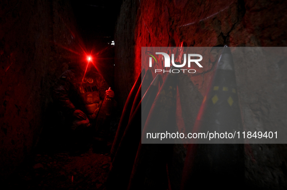 A serviceman of a self-propelled howitzer crew from Ukraine's 118th Separate Mechanized Brigade uses a headlamp with a red light in an ammun...