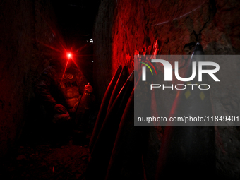 A serviceman of a self-propelled howitzer crew from Ukraine's 118th Separate Mechanized Brigade uses a headlamp with a red light in an ammun...