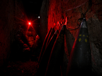 A serviceman of a self-propelled howitzer crew from Ukraine's 118th Separate Mechanized Brigade uses a headlamp with a red light in an ammun...