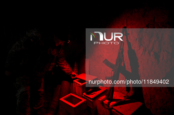 A serviceman of a self-propelled howitzer crew from Ukraine's 118th Separate Mechanized Brigade uses a headlamp with a red light in an ammun...