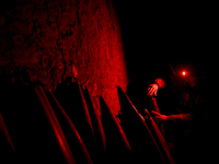 A serviceman of a self-propelled howitzer crew from Ukraine's 118th Separate Mechanized Brigade uses a headlamp with a red light in an ammun...